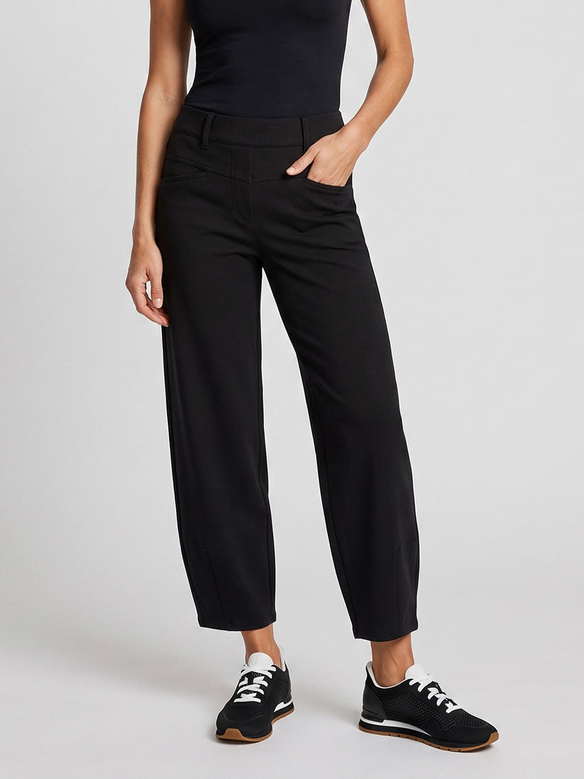 A model wearing black wide-leg cropped trousers, paired with a black top and black sneakers, shown from the chest down against a light gray studio background.