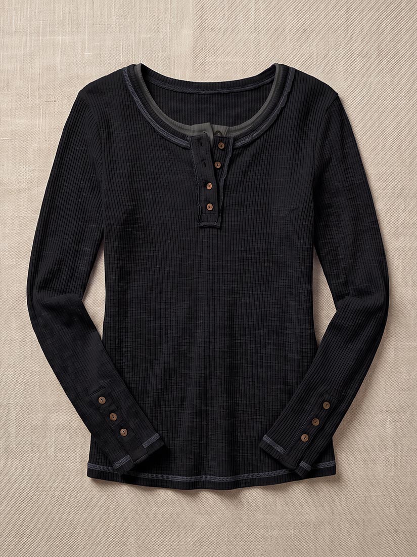 A dark charcoal gray ribbed long-sleeve henley shirt with brown buttons, laid flat on a textured beige background.