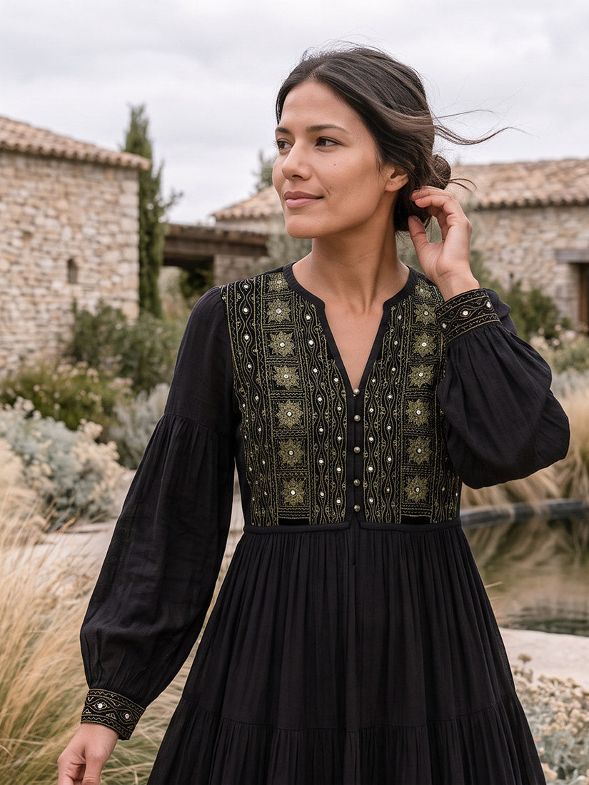 dark haired woman in black embroidered dress in rustic setting