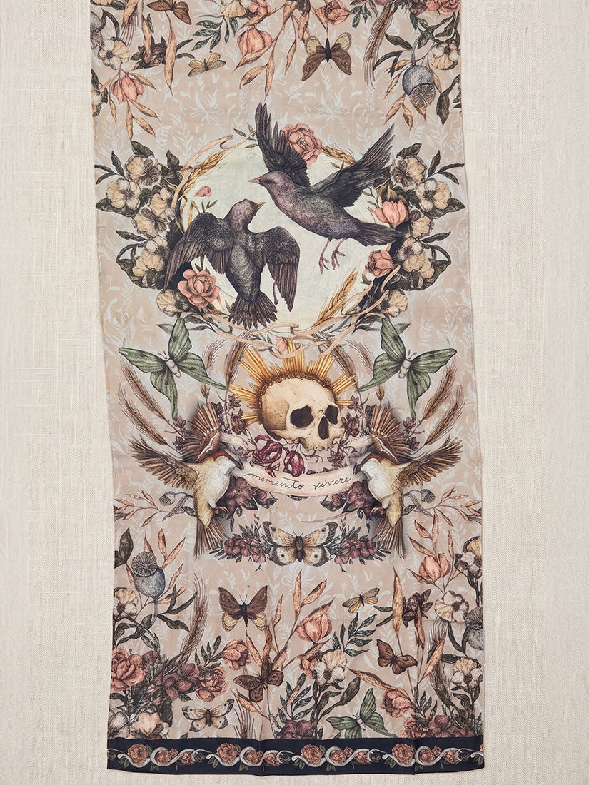 A vertical textile panel or tapestry featuring a detailed vintage-style gothic illustration with birds, a skull, butterflies, and floral motifs on a light beige background.