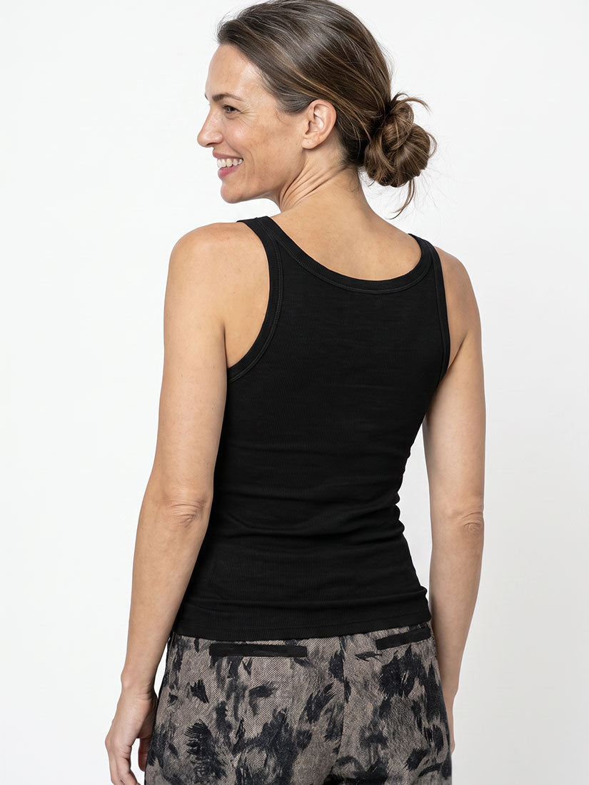 A woman shown from the back wearing a black sleeveless tank top and gray patterned leggings against a plain white studio background.