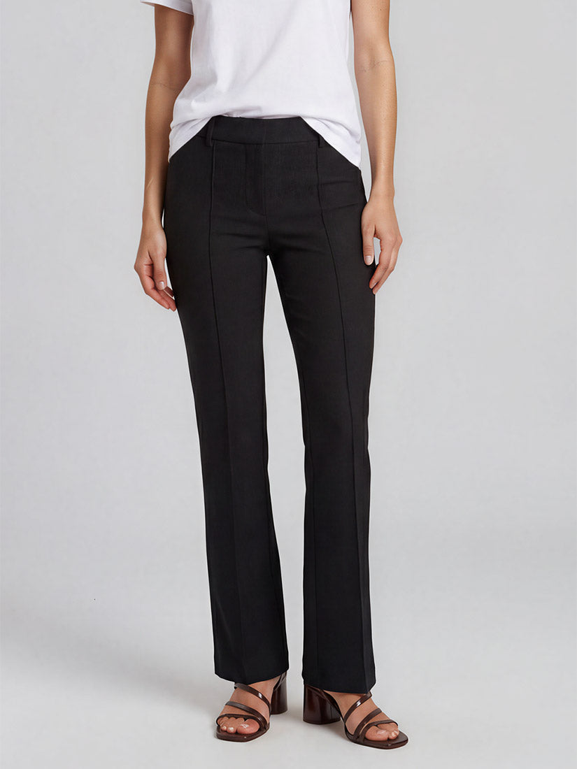 A model wearing black cambio  francoise wide-leg trousers, styled with a white t-shirt and brown strappy sandals, photographed against a light gray studio background