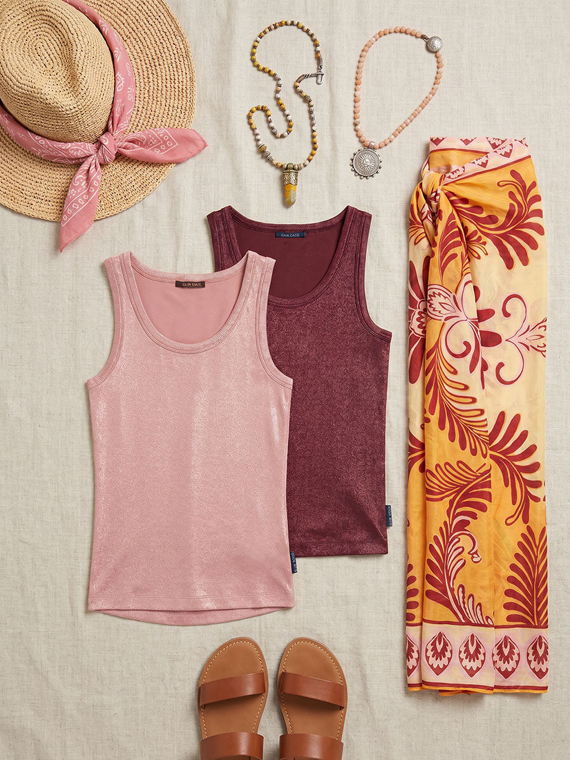 Pink tank top, maroon tank top, straw hat with pink band, sandals, and a patterned scarf on a beige background.