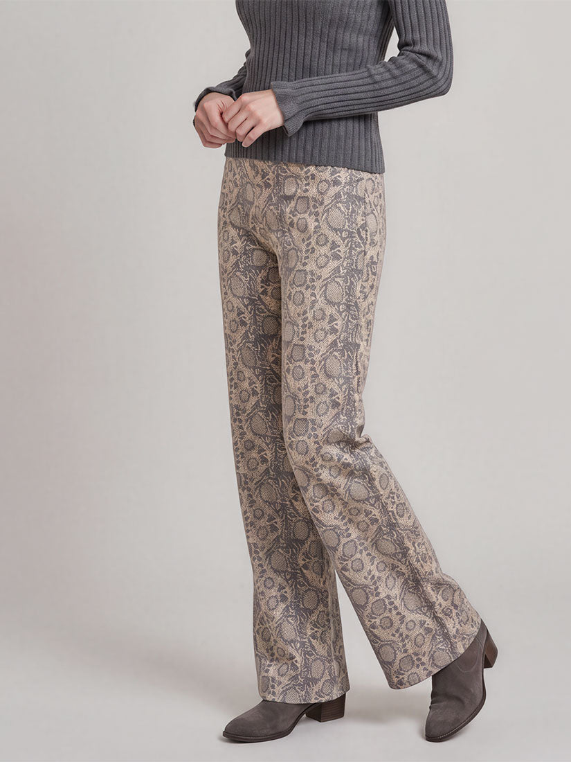A model is shown from the waist down wearing beige and gray patterned wide-leg trousers, a dark gray ribbed sweater, and gray suede ankle boots against a neutral studio background.