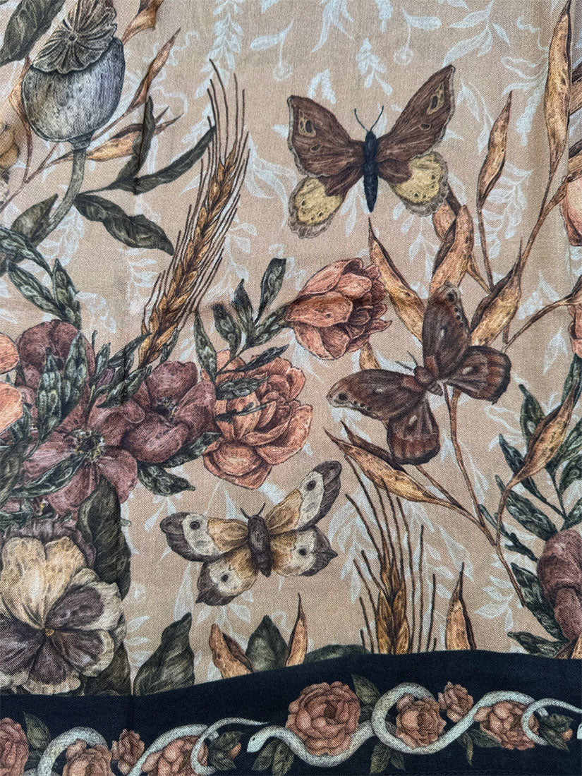 A close-up of a fabric or wallpaper pattern featuring vintage-style butterflies, roses, and wheat stems on a warm beige background, with a dark navy border at the bottom.