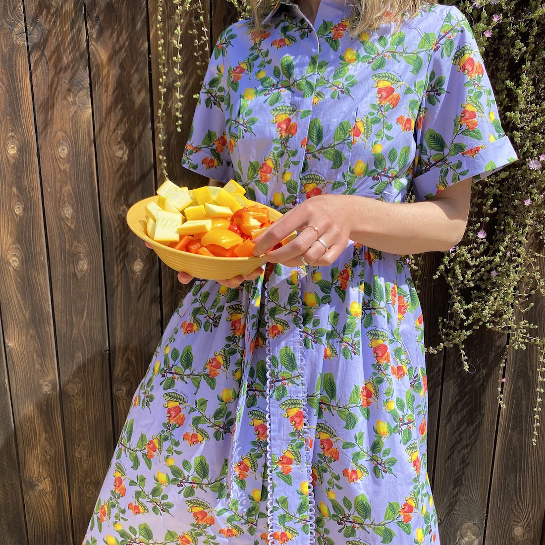girl holding fruit bowl in emily lovelock ss 22 shirt dress in lemon and pepper print.
